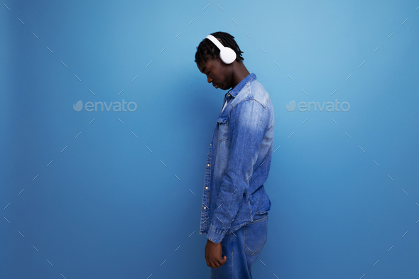 cool dude american man with dreadlocks in denim jacket listening to favorite music playlist with
