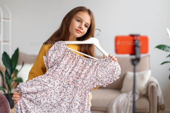 girl holding new dress and making remarks about its quality and price while recording a video blog