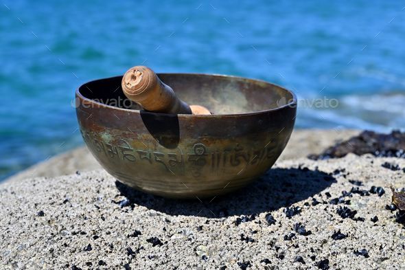 Singing bowl in front of Atlantic ocean. English translation of mantras. transform your impure body