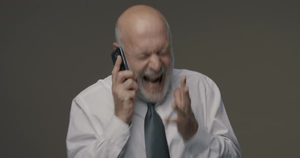 Angry senior businessman shouting on the phone, he is frustrated and disappointed