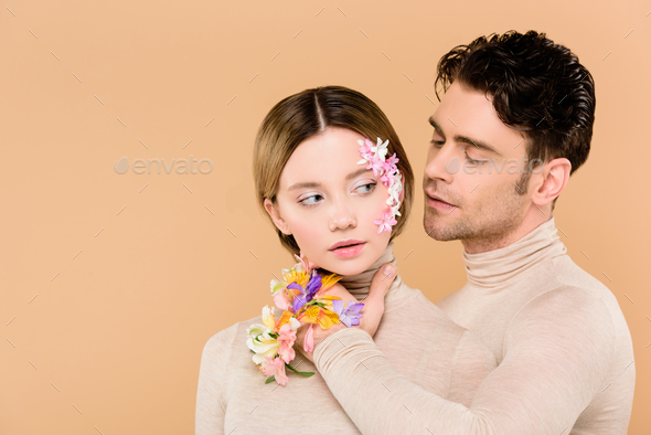 tender man with alstroemeria flowers on hand touching face of beautiful  girlfriend isolated on beige Stock Photo by LightFieldStudios