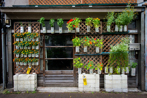 Old house in Tokyo with plants hanging in reused plastic bottle in front with suveillance camera