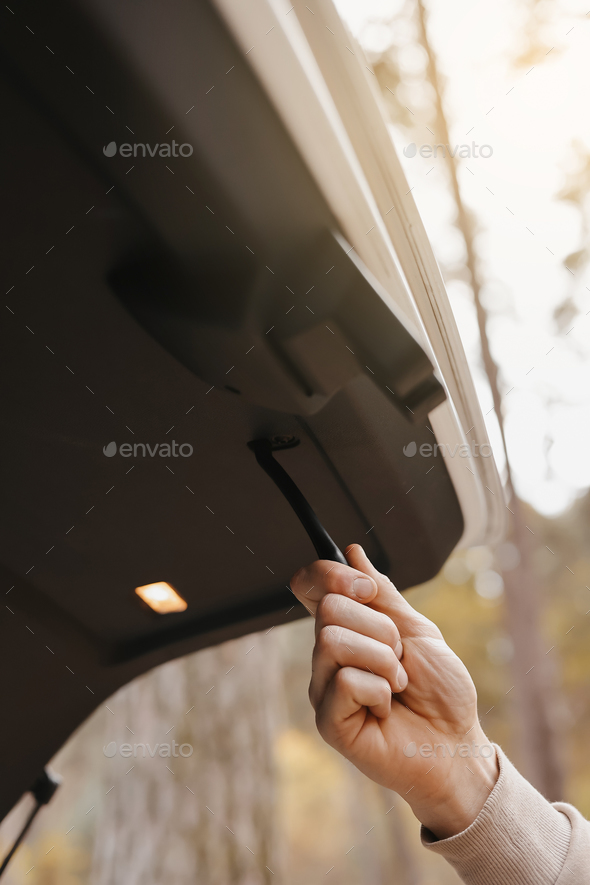 Unrecognisable man holds trunk handle and closes car trunk door