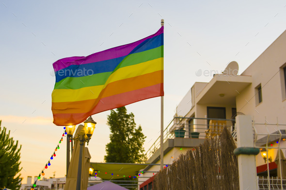 Flag lgbt against the backdrop of the sunet in an open-air bar
