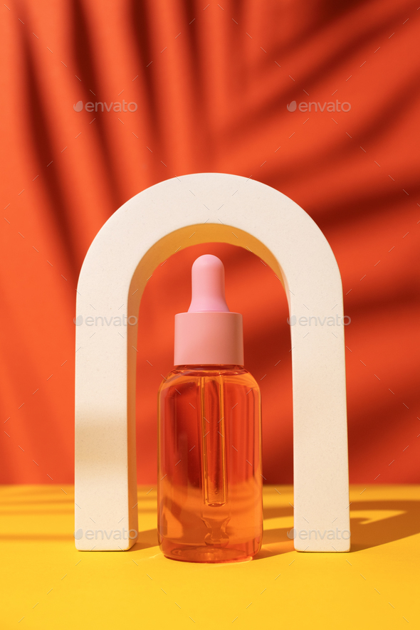 Cosmetic bottle with serum or oil in arch. Orange background with daylight and palm shadow.