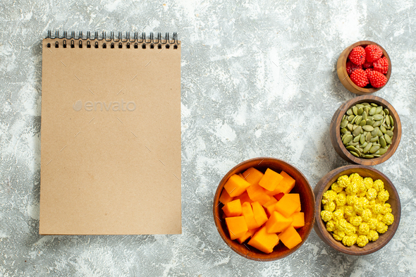 top view candies and pumpkin with seeds and notepad on white background copybook color candy fruit