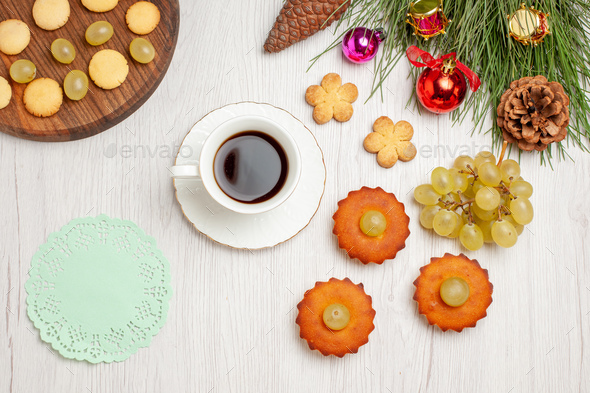 top view delicious little cakes with grapes and cup of tea on light white desk pie cake tea biscuit