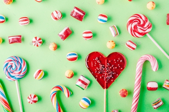 Closeup shot of candy canes and other candies on a green background - perfcet for a cool wallpaper