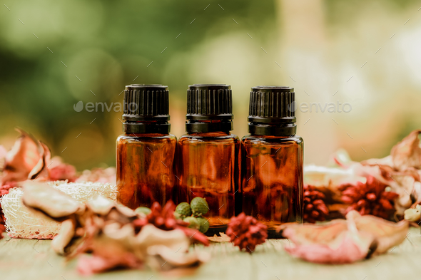 Closeup of small bottles of amber essential oil on a wooden fence under the sunlight