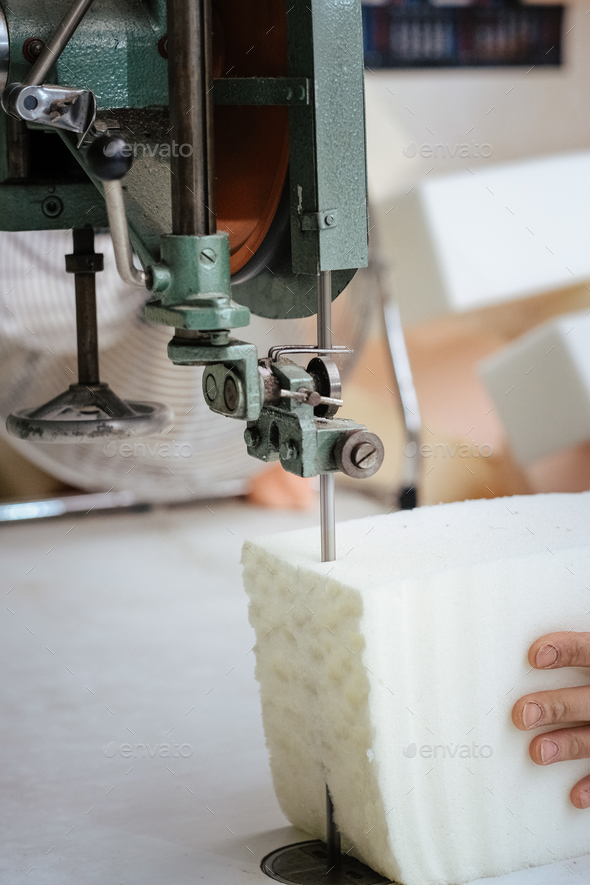 Vertical shot of a furniture maker cutting an upholstery foam using a foam cutter machine
