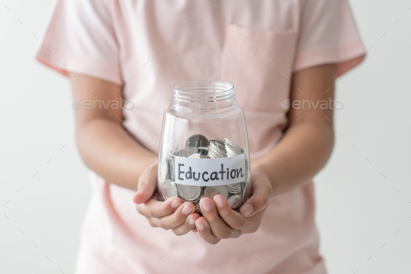 Kid holding her saving coins jar concept of savings money for future education school admission fee.