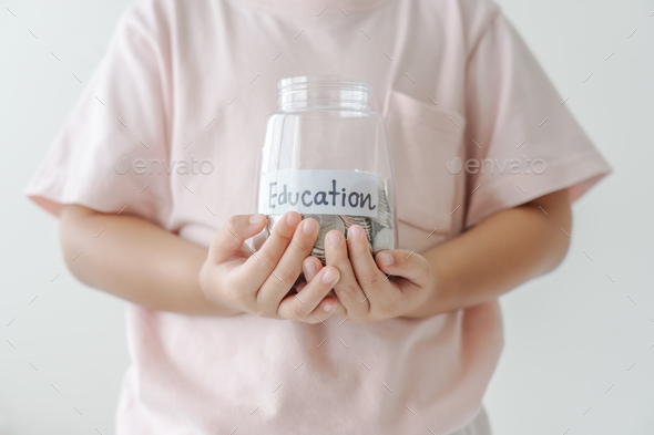Kid holding her saving coins jar concept of savings money for future education school admission fee.