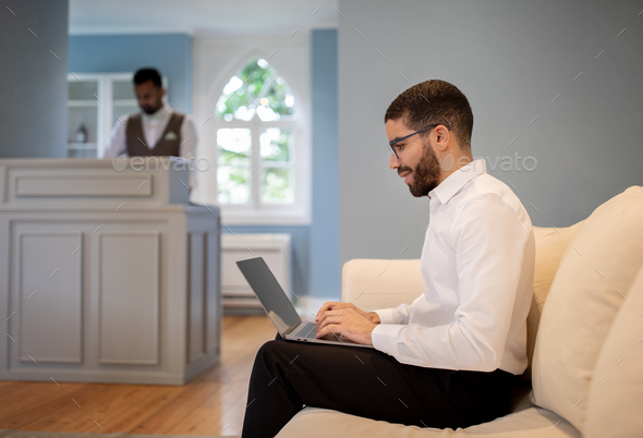 Middle Eastern Businessman Using Laptop Computer Sitting At Hotel Reception