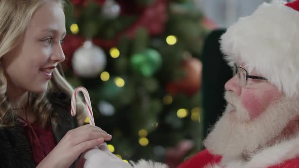 Girl hugs Santa Claus after he gives her a candy cane alt