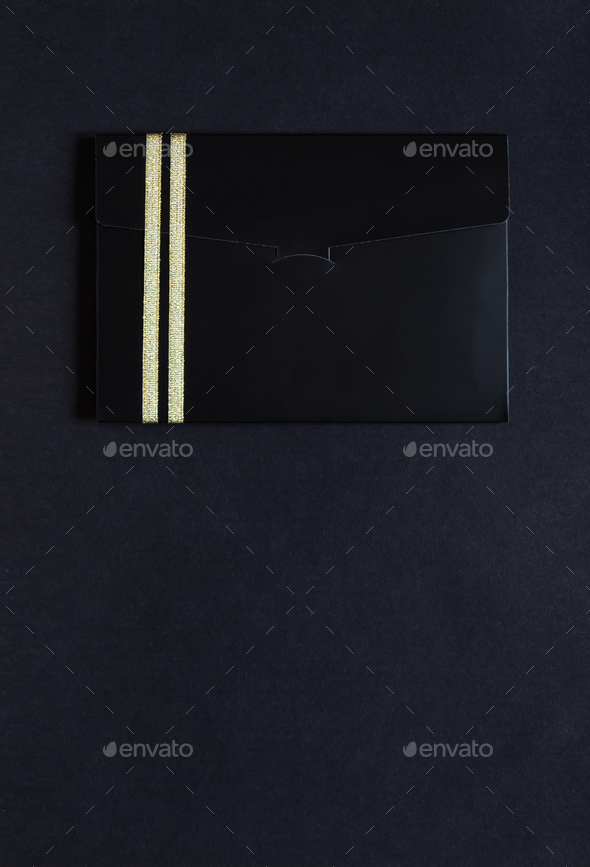 black envelope mockup, Flat Lay, on black background with copy space. Tied with a gold ribbon.