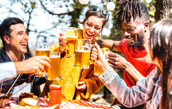 Young friends toasting beer pint at brewery garden venue - Stock Photo - Images
