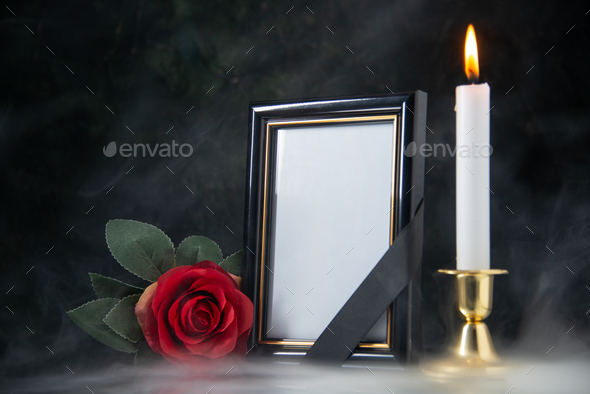 front view of burning candle with picture frame on a black background funeral evil war death