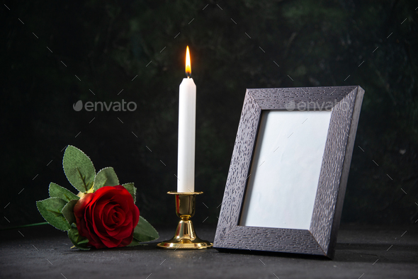 front view of burning candle with picture frame on dark background war funeral death