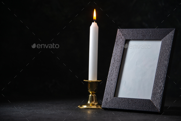 front view of burning candle with picture frame on dark background war funeral evil death