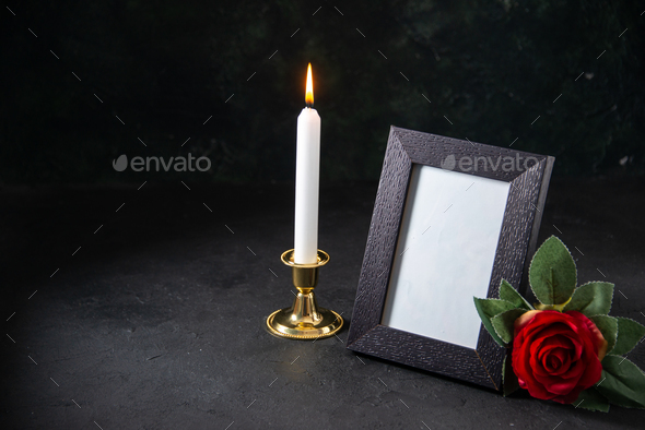 front view of burning candle with picture frame on dark desk funeral evil death war