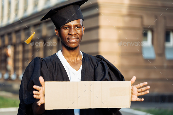 Poor black guy standing with cardboard sign on street looking for job. University or college