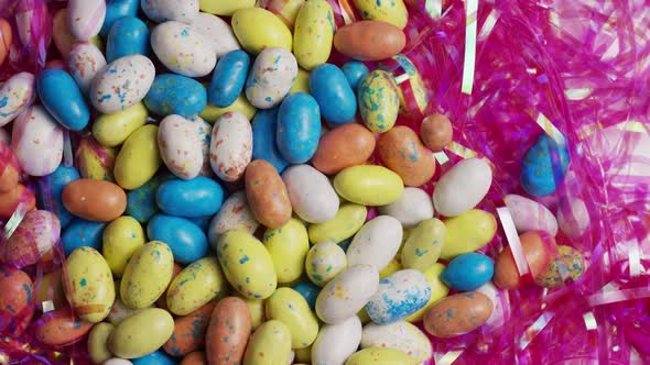 Rotating shot of colorful Easter candies on a bed of easter grass - EASTER alt