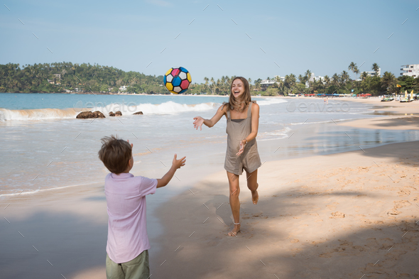 Happy mother and son playing ball at beach in summer sunny day - Stock Photo - Images
