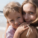Beautiful young mother and son hugging at beach in sunny summer day - PhotoDune Item for Sale