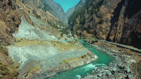 Beautiful Bhagirathi river flowing through stones under the bridge near the bank of Highway road