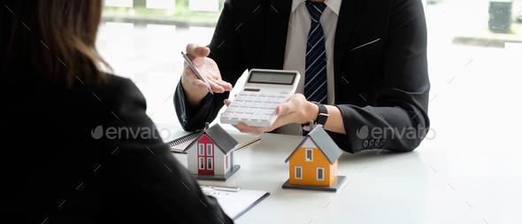 Real estate agents talk to client and offer good interest rates and calculate clients on mortgage - Stock Photo - Images