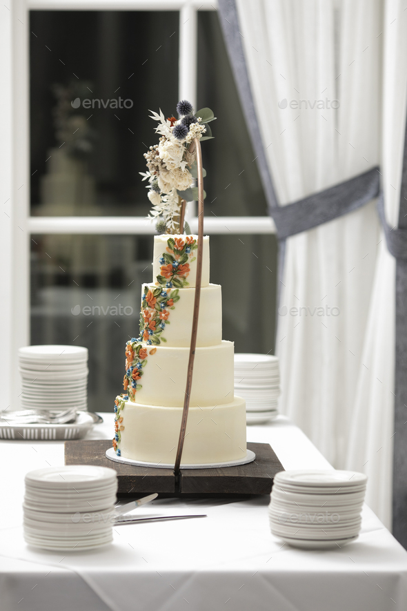 Four tiered ivory colored wedding cake on table at wedding reception. - Stock Photo - Images