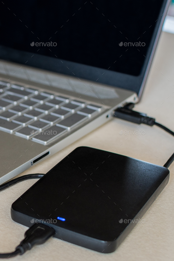 External hard drive connected to a laptop computer on a desk. A portable hard drive