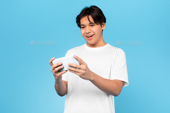 Chinese Guy Using Phone Playing Game Online On Blue Background