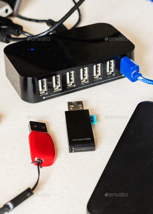 Vertical closeup of the flash drive, external drive, and multiple USB ports charger on a desk