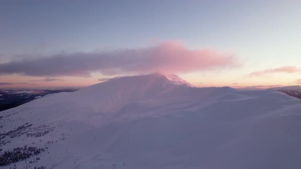 Drone Rising Above Mountain Top Covered in Clouds During Pink Sunset
