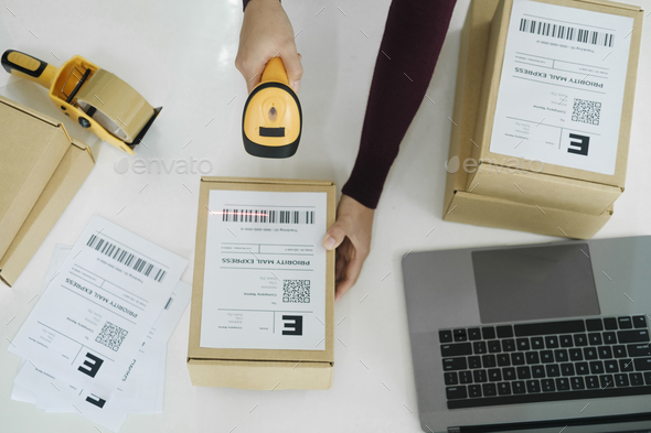 Female online business owner scan shipping label on parcel.