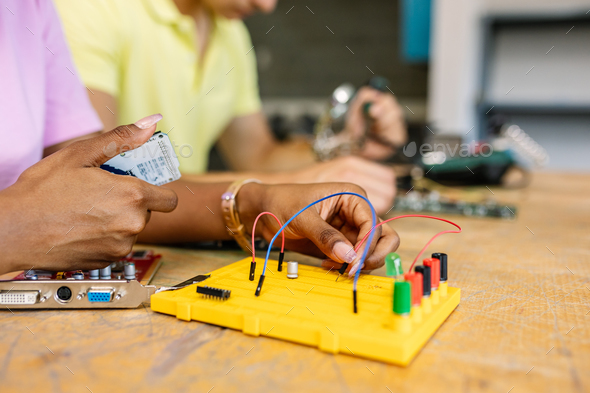 Close up female student hands creating electronic circuits and robotics at class