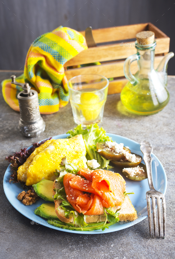 Omelette, fresh arugula and tomato salad and toasts with butter and salted salmon. Breakfast. - Stock Photo - Images