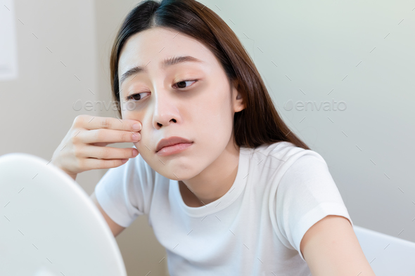 Asian young female stress looking mirror check have dark eye circles on face from staying up.