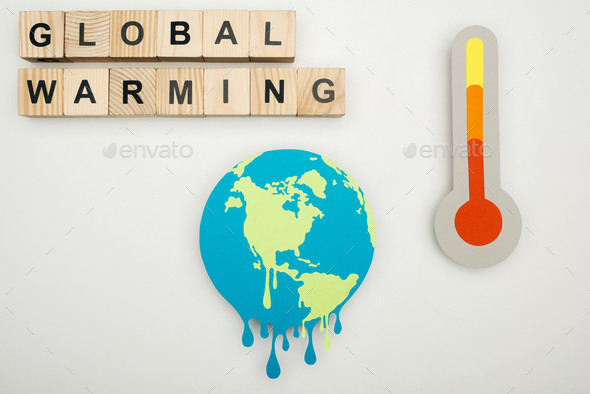 paper cut melting earth, wooden cubes with \'global warming\' lettering, and thermometer with hign