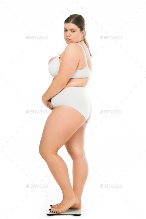 side view of sad young overweight woman in underwear standing on scales  isolated on white, lose Stock Photo by LightFieldStudios