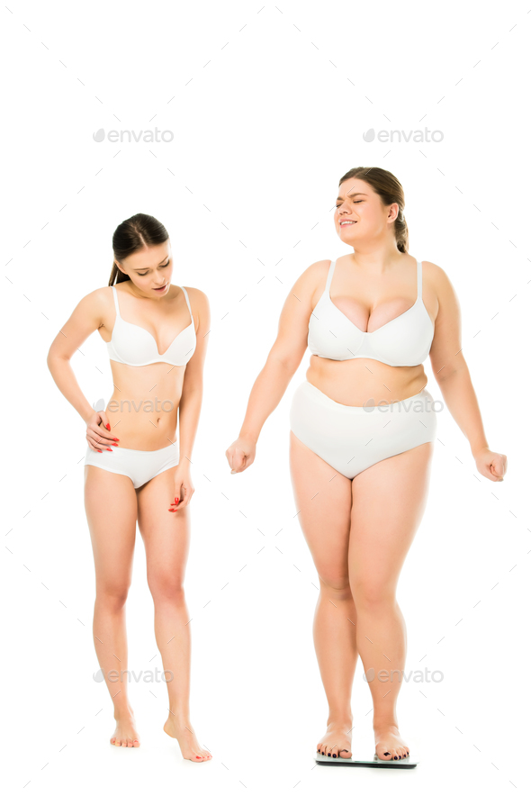 shocked slim woman in underwear looking at happy overweight woman on scales  isolated on white, body Stock Photo by LightFieldStudios