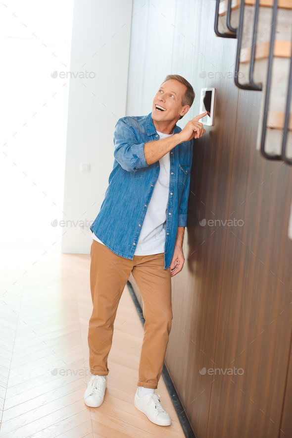excited handsome man using smart house control panel at new home