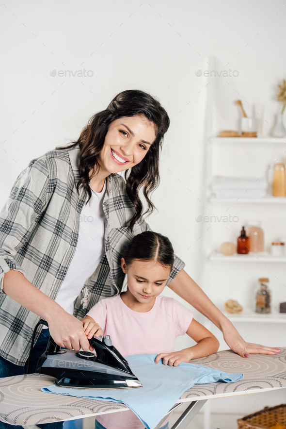 mother in grey shirt and daughter in pink t-shirt ironing at home