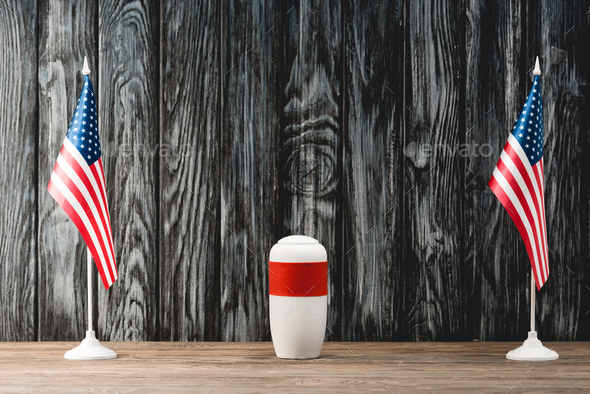 funeral urn with ashes near american flags