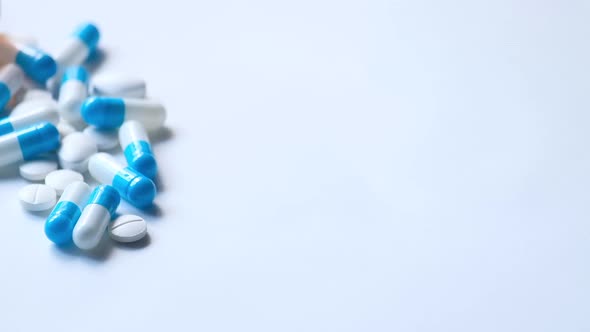 White and Blue Capsule Spilling on White Background  alt
