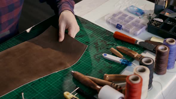 The Process of Manufacturing a Leather Wallet Handmade. The Wizard Makes a Mark on the Leather Bark