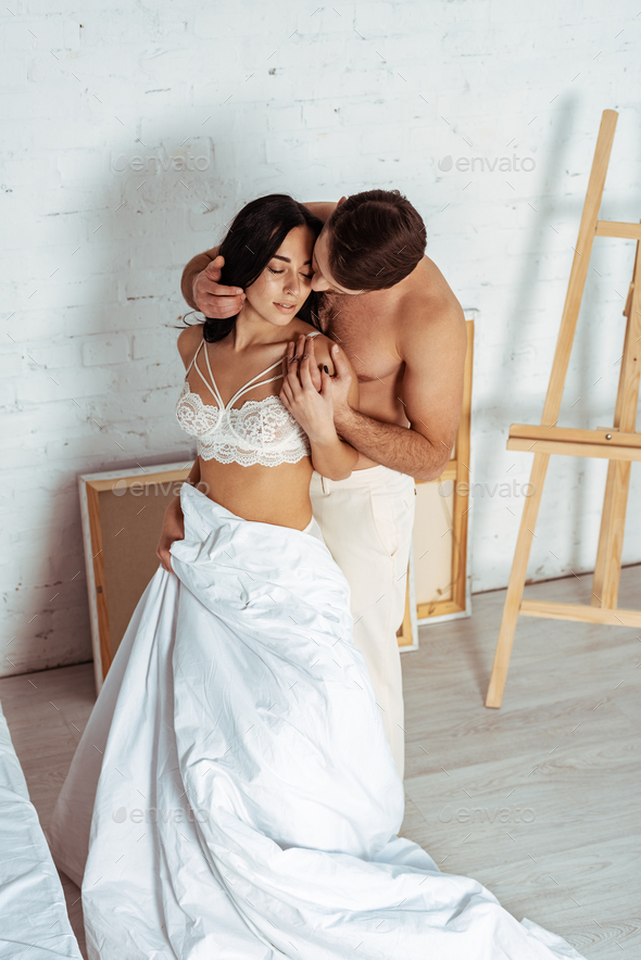 beautiful woman in lace bra kissing handsome man in bedroom Stock Photo by  LightFieldStudios