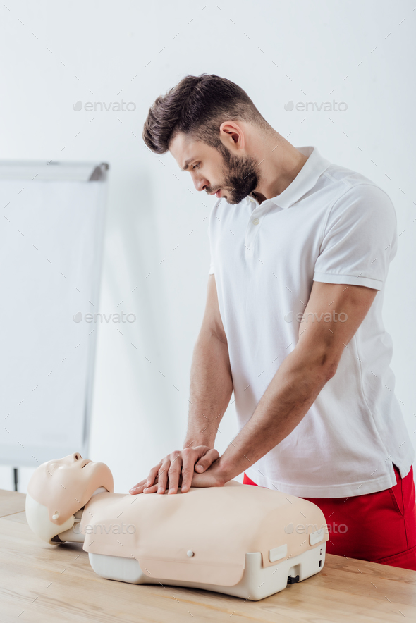 handsome man using chest compression technique on dummy during cpr training