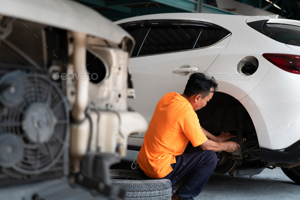 A auto mechanic checking the condition of a car\'s brake discs and the condition of the tires